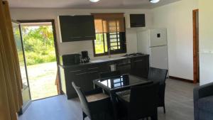a kitchen with a table and a white refrigerator at HUAHINE- Fare Montagne in Parea