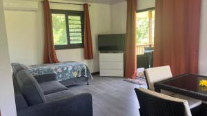 - un salon avec un lit, un canapé et une télévision dans l'établissement HUAHINE- Fare Le vent, à Parea