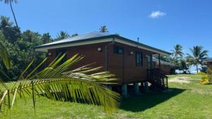 a small house with a grassy yard in front at HUAHINE- Fare la Mer in Parea