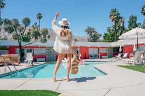 a woman in a hat standing by a swimming pool at The Muse Hotel Palm Springs in Palm Springs +188 photos