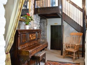 an old piano in a room with a staircase at East House Farm in Beckermonds