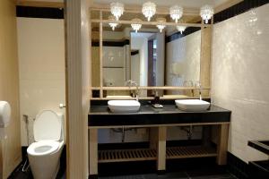 a bathroom with two sinks and a toilet and a mirror at Methavalai Residence Hotel in Bangkok