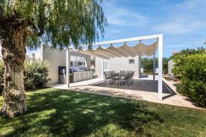 a patio with a table and chairs and a tree at Villa Paolo in Noto Marina