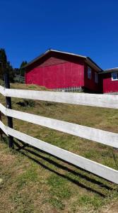una cerca blanca delante de un granero rojo en Casa amoblada, en Compu