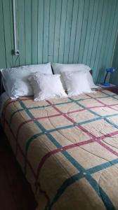 una cama con almohadas blancas encima en Casa amoblada, en Compu