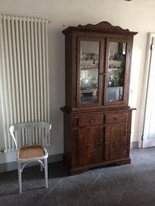 une armoire en bois et une chaise dans la chambre dans l'établissement Hochwertige Wohnung Im Turm Schlösschen, à Montemerano