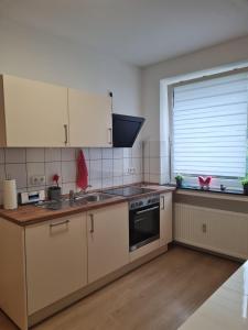 a kitchen with white cabinets and a stove and a window at Zentrale, Liebevoll Eingerichtete Ferienwohnung in Monheim