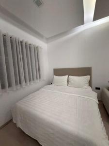 a white bedroom with a bed with white sheets and pillows at Ani Apartment with Fireplace in Tirana