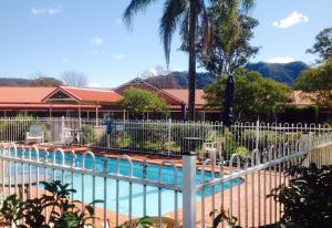 a white fence around a swimming pool with a pool at Gloucester Country Lodge Motel in Gloucester