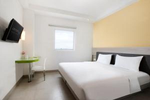 a white bedroom with a bed and a table at Amaris Hotel Pettarani - Makassar in Makassar