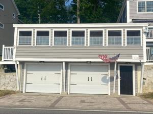 a house with two garage doors and an american flag at Cozy Cottage Alton Bay in Alton