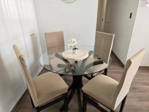 ein Glastisch mit Stühlen und einer Vase mit Blumen darauf in der Unterkunft Acogedor y amplio Departamento A 5 min del centro in Rancagua