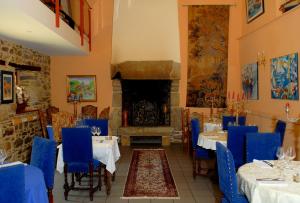 uma sala de jantar com mesas e cadeiras azuis e uma lareira em Domaine De Kermodest em Quemper-Guézennec