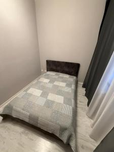 een kleine slaapkamer met een bed met een geruite deken bij Jurges Relax Graza in Daugavpils