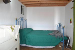ein Schlafzimmer mit einem Bett mit einer grünen Decke in der Unterkunft Ferienhaus für 2 Personen ca 60 m in Feteira, Azoren Terceira in Angra do Heroísmo
