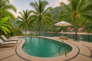 a swimming pool with palm trees in a resort at Boca de Tomatlán Ocean Frontage Boutique Hotel in Puerto Vallarta