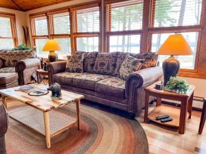 a living room with a couch and tables and windows at The Tinker Bell on Ossipee Lake in Ossipee