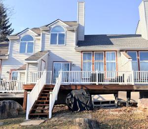 a house with a wooden deck in front of it at Lake and Ski Escape with Hot Tub Coming Soon in Lake Harmony