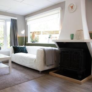 a living room with a white couch and a fireplace at Celisa S Häuschen in Hoenderloo