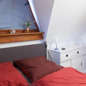 une chambre avec un lit rouge et une fenêtre avec un vase dans l'établissement Ferienwohnung Moin Moin In Friedrichskoog Spitze, à Friedrichskoog 4 autres photos