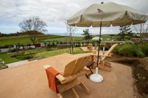 zwei Stühle und ein Sonnenschirm auf einer Terrasse in der Unterkunft Ferienhaus für 4 Personen ca 120 qm in Algarvia, Azoren Sao Miguel in Algarvia