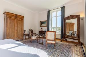 ein Schlafzimmer mit einem Bett, einem Spiegel und einem Tisch in der Unterkunft Château de Penfrat in Gouesnach