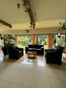 un soggiorno con divani neri e tavolo di Hotel Abetaia a Villa Gesell