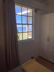 a bedroom with a window with a view of the ocean at Kingdom Rentals - AirBnCar in Roseau