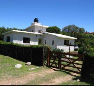 een wit huis met een hek ervoor bij Rancho Laramie in Huerta Grande