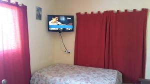 een slaapkamer met rode gordijnen en een tv aan de muur bij Rancho Laramie in Huerta Grande