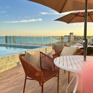 un patio con sedie e un tavolo con un ombrellone di FLAT Beira Mar Tamandare a Tamandaré