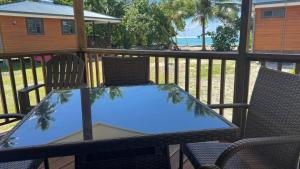 une table et des chaises sur un balcon avec vue sur la plage dans l'établissement HUAHINE- Fare Arc-en-Ciel, à Parea