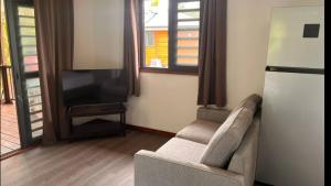 un salon avec un canapé et une télévision dans l'établissement HUAHINE- Fare Arc-en-Ciel, à Parea