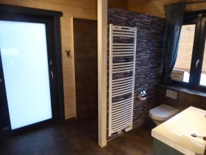 ein Badezimmer mit Toilette und einer Ziegelwand in der Unterkunft Harz - Blockhaus, 4 und 5 Sterne Blockhäuser, Sauna und Kamin, RH in Hahnenklee-Bockswiese + 29 Fotos