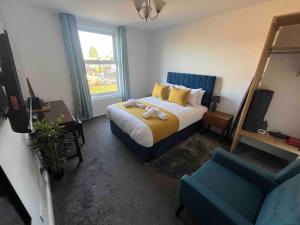 ein Schlafzimmer mit einem Bett, einem Fernseher und einem Stuhl in der Unterkunft The Linden Leaf Rooms in Nottingham