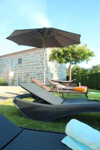 eine Terrasse mit Sonnenschirm und Tisch und Stühlen in der Unterkunft Ferienhaus mit Privatpool für 6 Personen ca 290 m in Paradela, Regio Norte Minho in Paradela