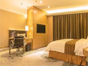 a hotel room with a bed and a desk and a television at The Summit Hotel in Zhongshan