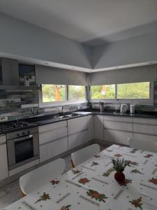 a white kitchen with a table and chairs and windows at Casa con encanto serrano in Villa General Belgrano