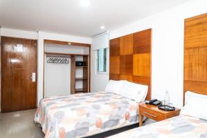 a bedroom with two beds and a wooden headboard at Suites Gaby Cancun in Cancún