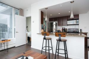 a kitchen with two bar stools and a counter at Sub-Penthouse Condo with Jacuzzi Pool Sauna & Gym in Vancouver