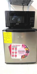 un micro-ondes posé sur un réfrigérateur dans l'établissement Habitación privada en Playa Dorada con Kitchenette, à ArraijÃ¡n