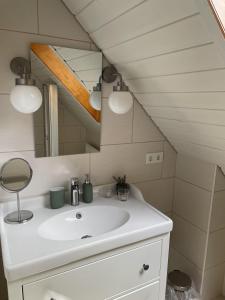 ein Badezimmer mit einem weißen Waschbecken und einem Spiegel in der Unterkunft Ferienhaus im Fachwerkstil mit Sauna und Garten in Thomasburg