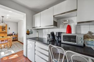 una cucina con mobili bianchi e un piano di lavoro nero di George Countryhouse a Lissendorf