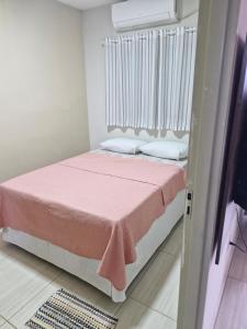 a bedroom with a bed with a pink blanket at Hospedagem do Elias in Cuiabá