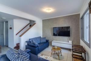 un salon avec un canapé bleu et une télévision dans l'établissement Casa em Cabo Frio a 200m da praia ADP001, à Peró