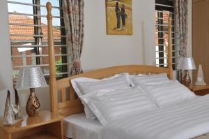 Un dormitorio con una cama con sábanas blancas y una ventana. en Calm Suites Kampala, en Kampala