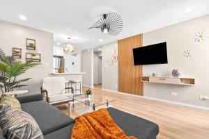 ein Wohnzimmer mit einem Sofa und einem Fernseher an der Wand in der Unterkunft Peaceful Modern HNL Getaway in Honolulu