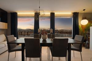 een eetkamer met een tafel en stoelen en een groot raam bij The Grand Horizon By Paramount in Tromsø +21 foto's