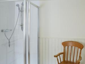 ein Holzstuhl neben einer Dusche in der Unterkunft Grooms Cottage in Elsdon