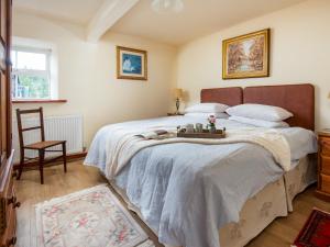 ein Schlafzimmer mit einem großen Bett und einem Stuhl in der Unterkunft Grooms Cottage in Elsdon